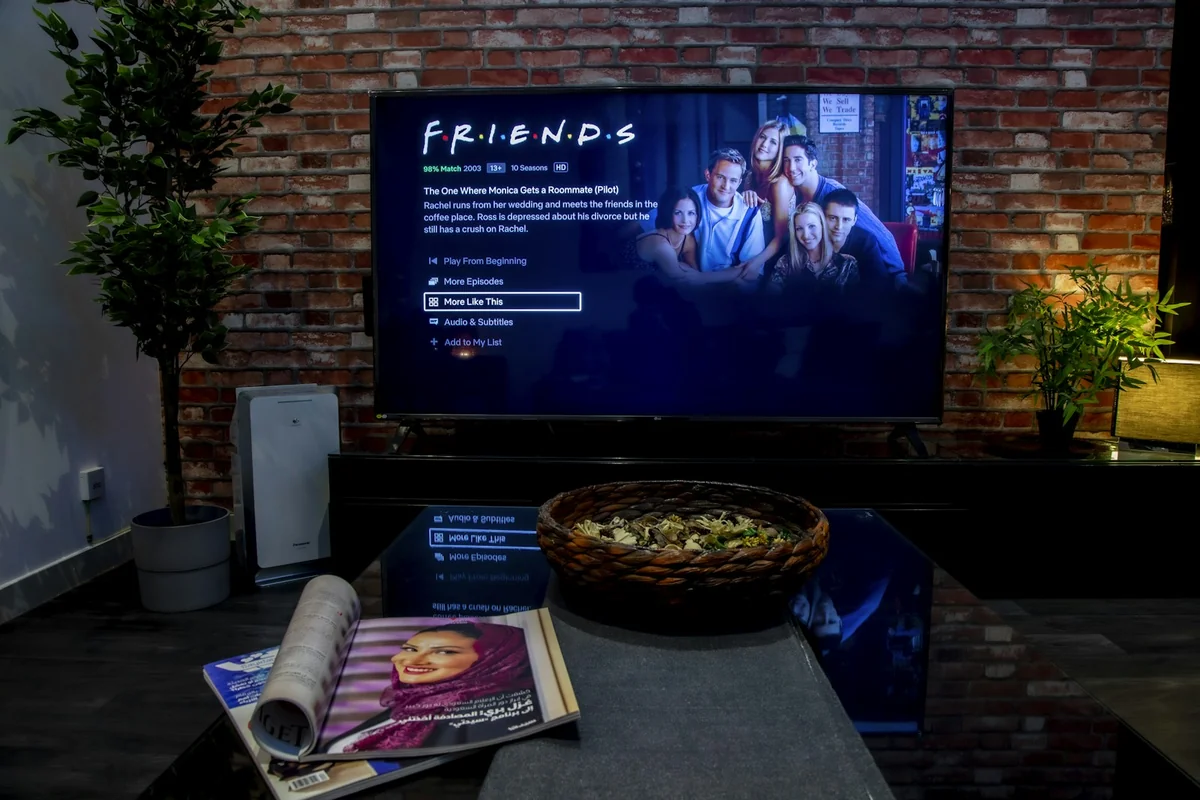Man holding a TV remote in front of a large flat screen TV