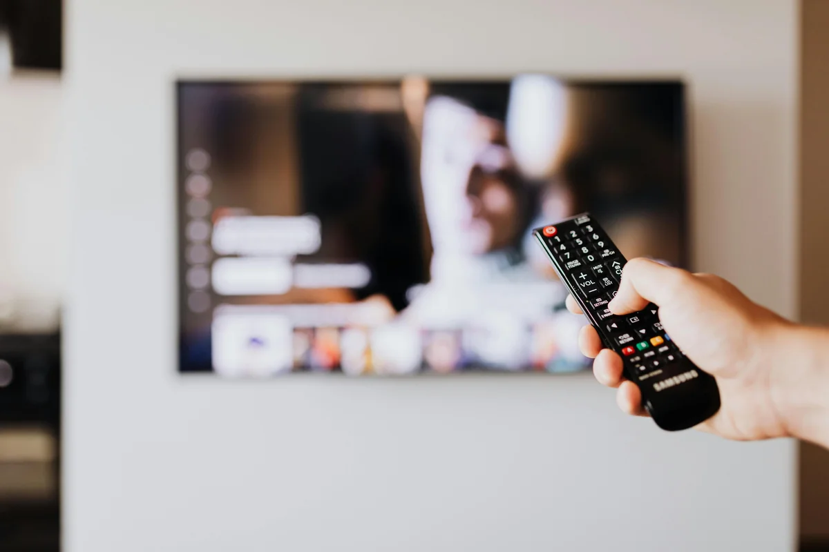 Fjarrkonroll riktad mot en TV som visar en IPTV-programguide